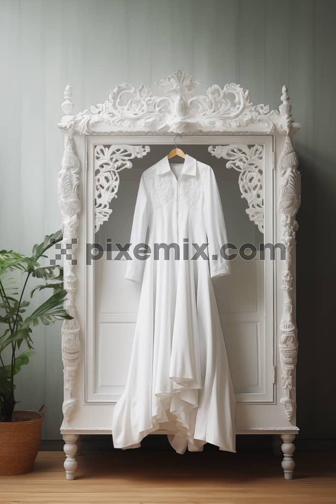 An image of an elegant white dress hanging from a intricate wardrobe.