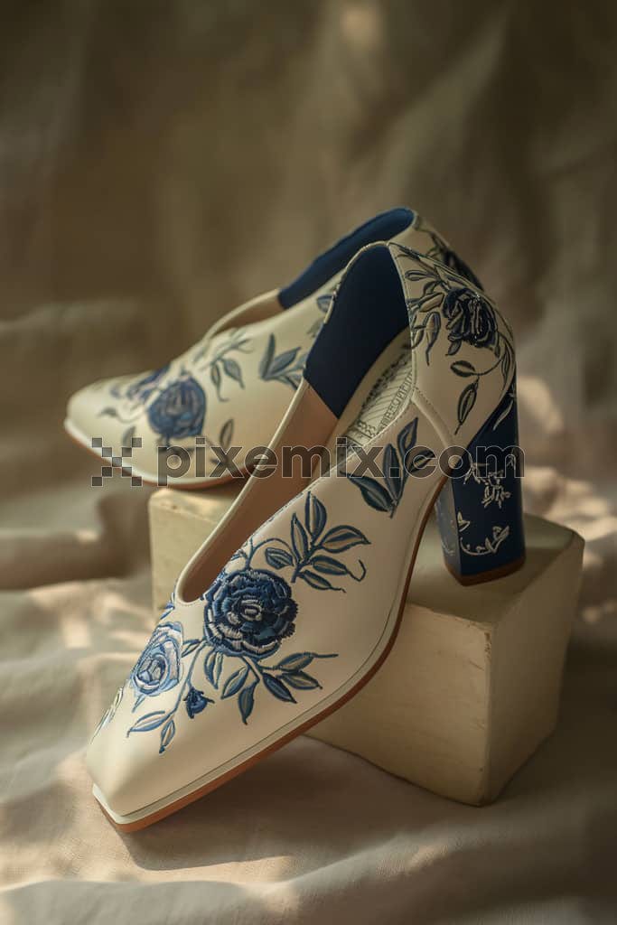 An image of blue embroided shoes with an off white background.