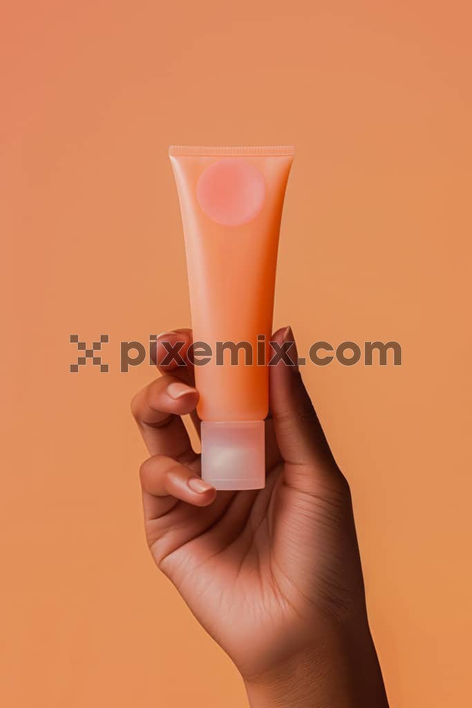 The image shows a black woman's hand holds an orange cream tube.